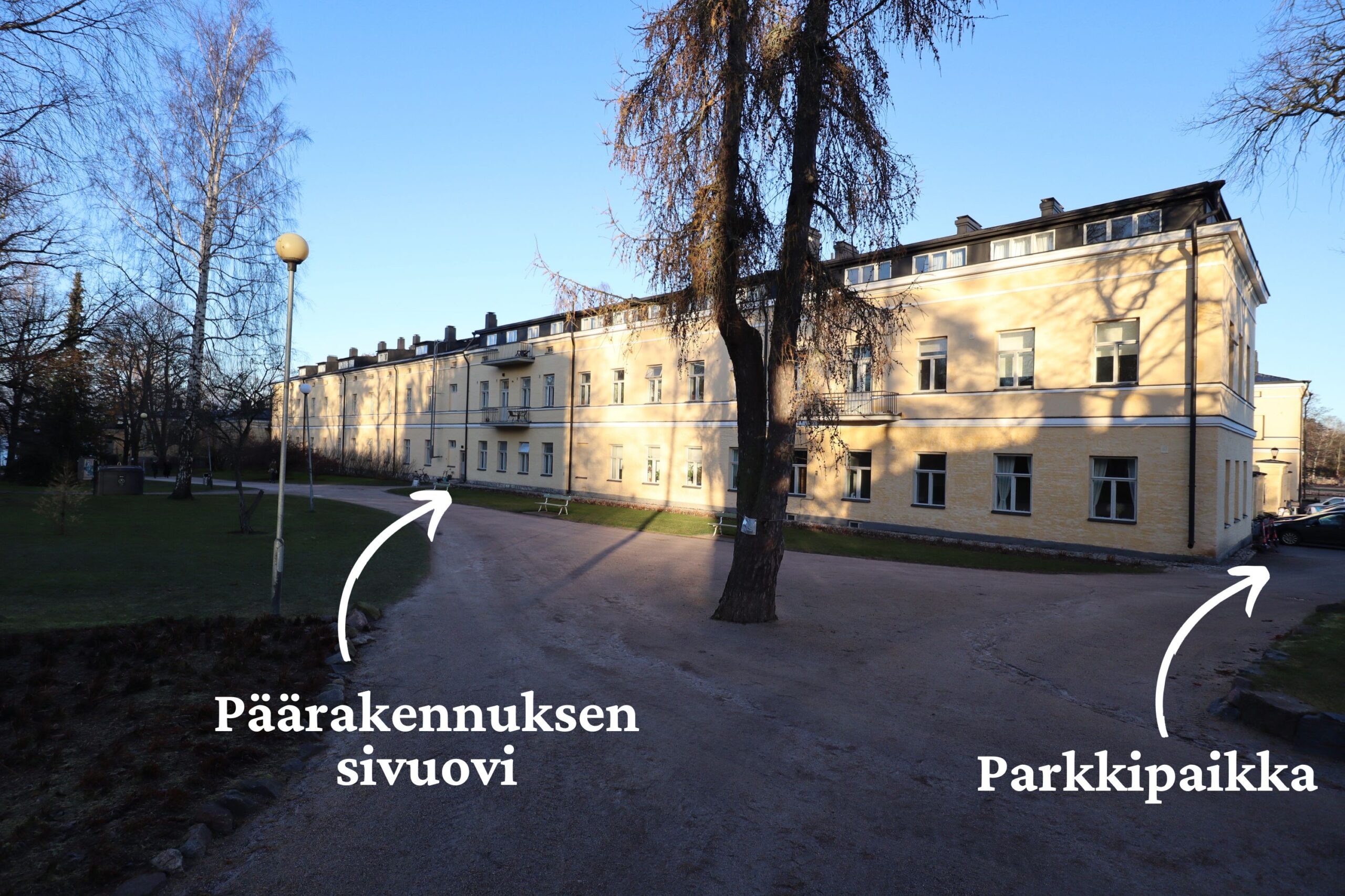 Kuvassa on Lapinlahden päärakennuksen eteläinen kylki ja nuolet, jotka osoittavat sivuovelle ja parkkipaikalle