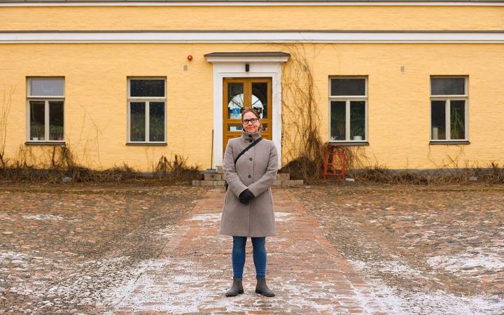 Kuvassa nainen seisoo Lapinlahden vanhan sairaalan edustalla huurteisella pihalla.
