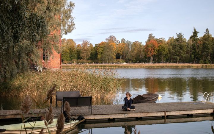 Kuvassa laituri ja Venetsia-rakennus, laiturilla nuori nainen.