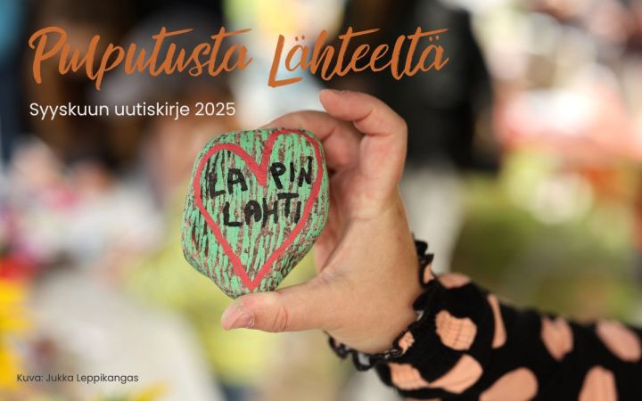 Käsi pitelee maalattua kiveä, jossa vihreällä pohjalla punainen sydän.