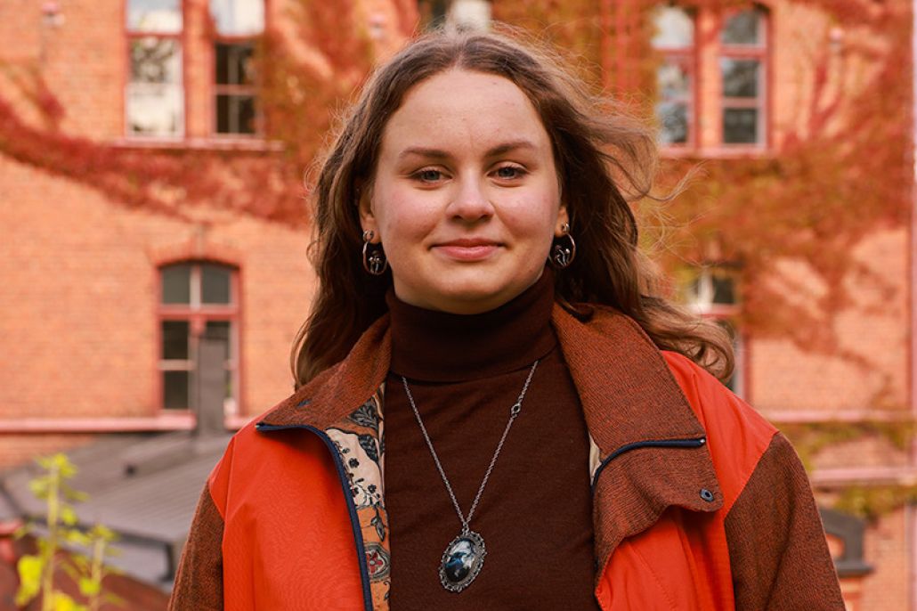 Nuori nainen seisoo vanhan rakennuksen edessä.