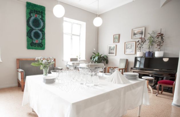 Kuvassa etualalla on suuri katettu pöytä Aleksis Kiven salongissa.