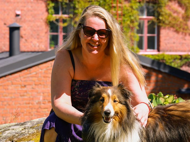 Pitkähiuksinen nainen ja pitkäkarvainen koira auringossa Lapinlahdessa.