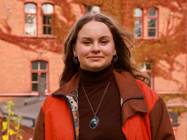 Nuori nainen seisoo vanhan rakennuksen edessä.