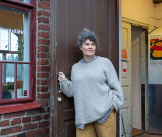 Nainen seisoo avatun oven edessä.