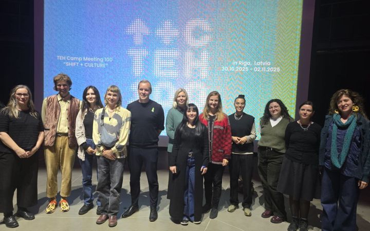 Ryhmäkuva ihmisistä TEH-valkokankaan edessä