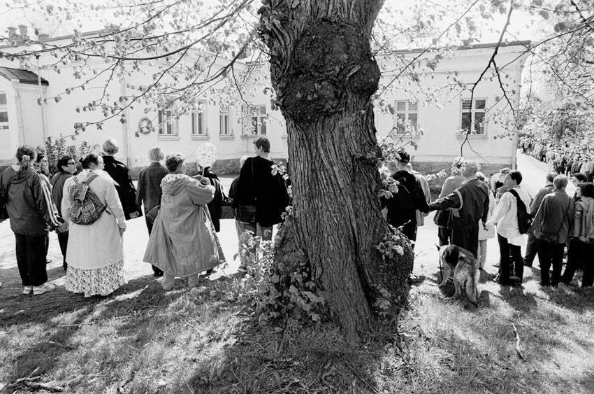 Mustavalkoisessa kuvassa ihmisiä pitää toisiaan kädestä ja muodostaa jonon Lapinlahden sairaalan ympärille.