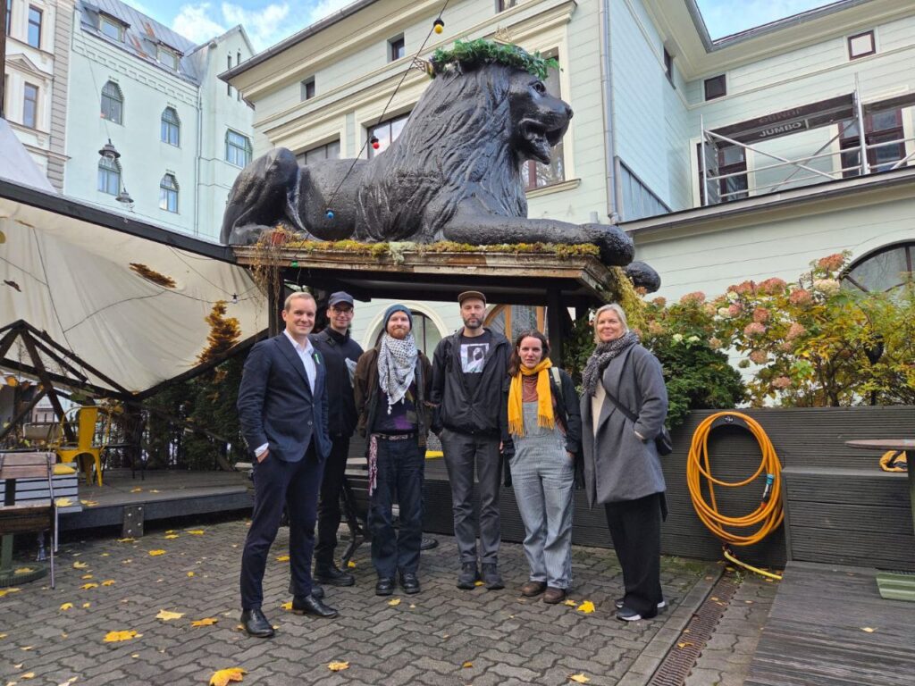 Joukko ihmisiä leijonapatsaan edustalla.