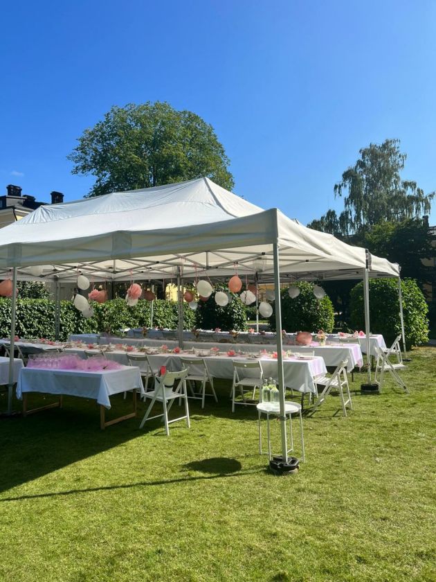 Kuvassa on puutarhapihalle laitettuja katoksia ja katettuja pöytiä.