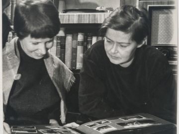 Helvi Juvonen ja Sirkka Meriluoto katselevat pöydällä olevaa valokuva-albumia.