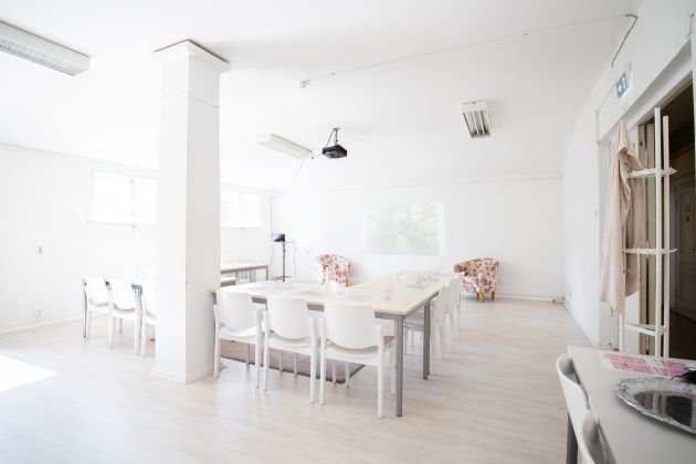 Kuvassa on pöytiä, tuoleja ja Pylvässalin pylväs.