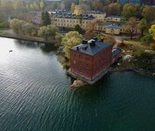 Ilmakuva veden yltä Venetsia-tiilitalosta ja Lapinlahden alueesta.
