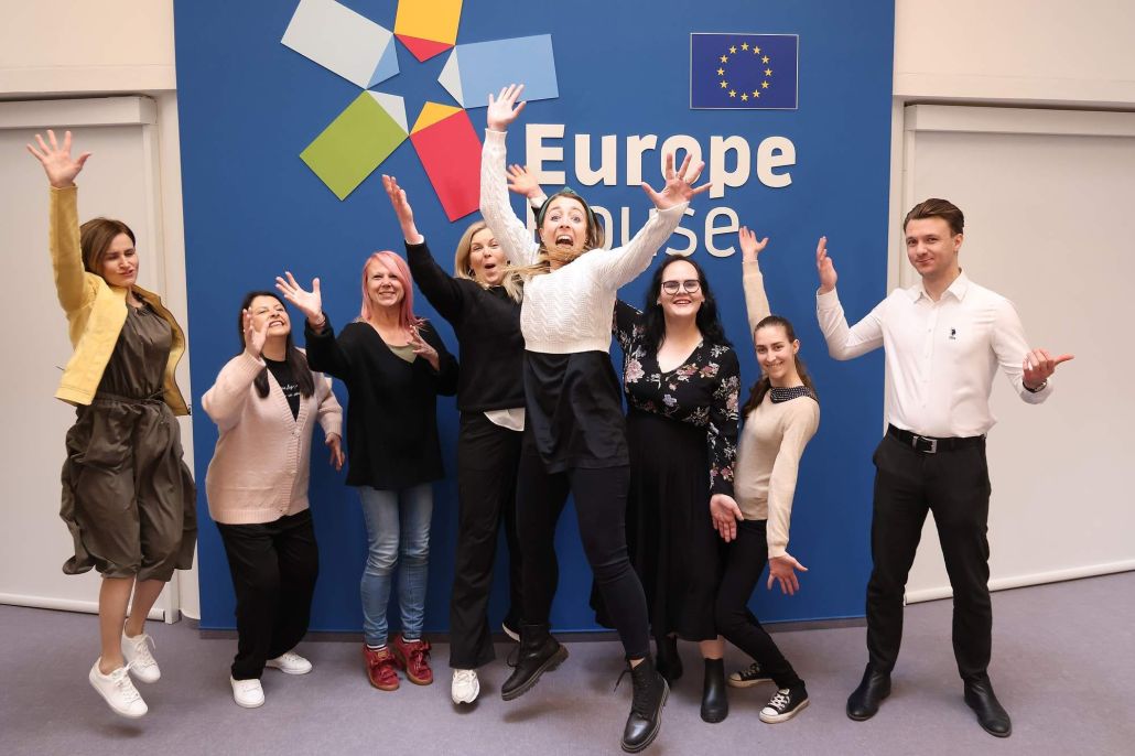 Kuvassa joukko iloisia ihmisiä Europe-kyltin edessä.