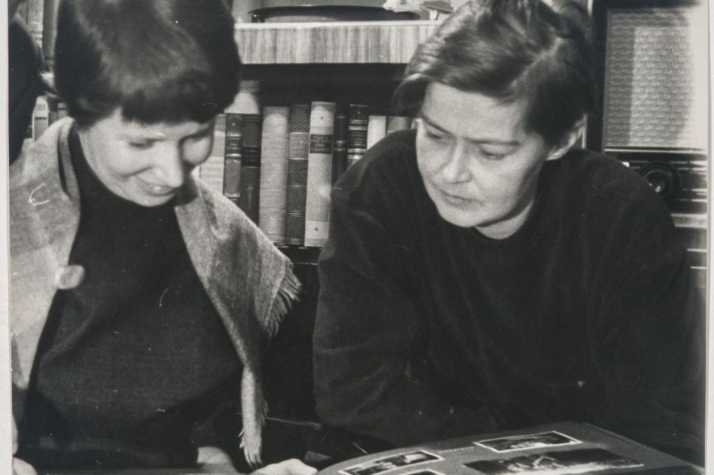 Helvi Juvonen ja Sirkka Meriluoto katselevat pöydällä olevaa valokuva-albumia.