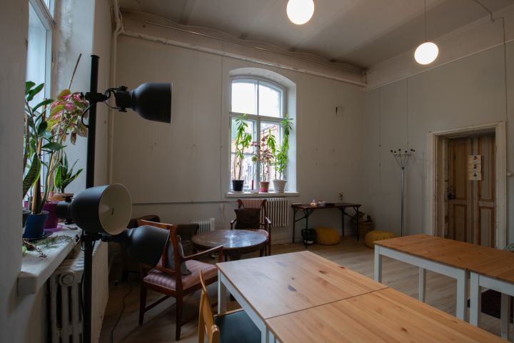 Kuvassa on Venetsia-talon Avoin tila nurkasta kuvattuna. Etualalla on pöytiä ja tuoleja, vasemmalla lamppuja.