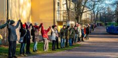 Vuoden 2018 Muuri-tapahtumassa päärakennuksen seinän edessä seisoo ihmisiä käsi kädessä silmänkantamattomiin.