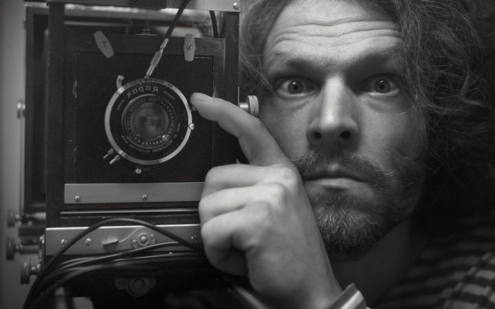 Jakub Berkowits ja hänen valokuvansa Self Portrait Day 289, jossa mies katsoo kameraan vanha kamera kädessään.