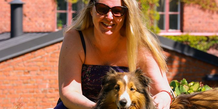 Pitkähiuksinen nainen ja pitkäkarvainen koira auringossa Lapinlahdessa.