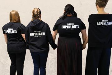 Neljä naista mustissa Kaikkien Lapinlahti -t-paidoissa selkäpuolelta kuvattuna