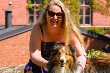 Pitkähiuksinen nainen ja pitkäkarvainen koira auringossa Lapinlahdessa.