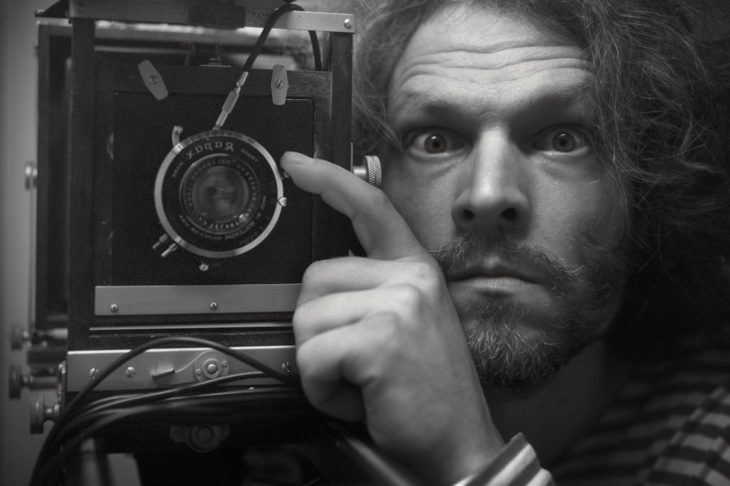 Jakub Berkowits ja hänen valokuvansa Self Portrait Day 289, jossa mies katsoo kameraan vanha kamera kädessään.