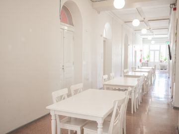 Kuvassa on Aleksis Kiven käytävä, jolla on pöytiä jonossa ja tuoleja.