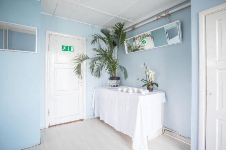 Kuvassa oikealla on katettu pöytä, jonka päällä on astioita ja palmu. Vasemmalla on Sinisen huoneen ovi.