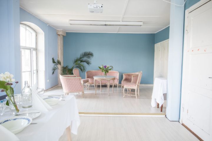 Kuvassa on Sinisen huoneen huonekaluja, huonekasvi ja katettu pöytä.