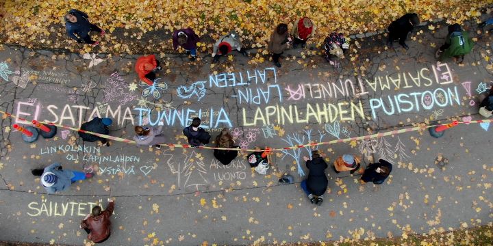 Ilmakuva kevyen liikenteen väylästä, jolla ihmiset kirjoittavat mielipiteitä liidulla asfalttiin