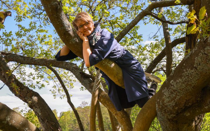 Kuvassa nainen kiivennyt puuhun