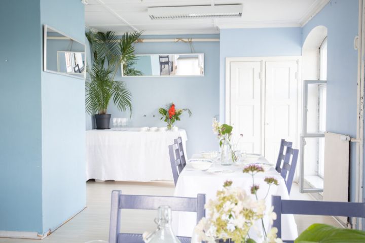 Kuvassa on katettuja pöytiä, astiakomero ja palmu.