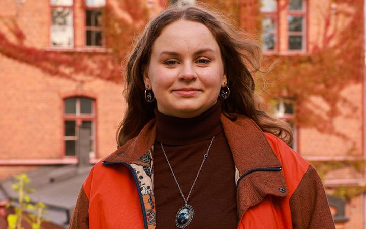 Nuori nainen seisoo vanhan rakennuksen edessä.