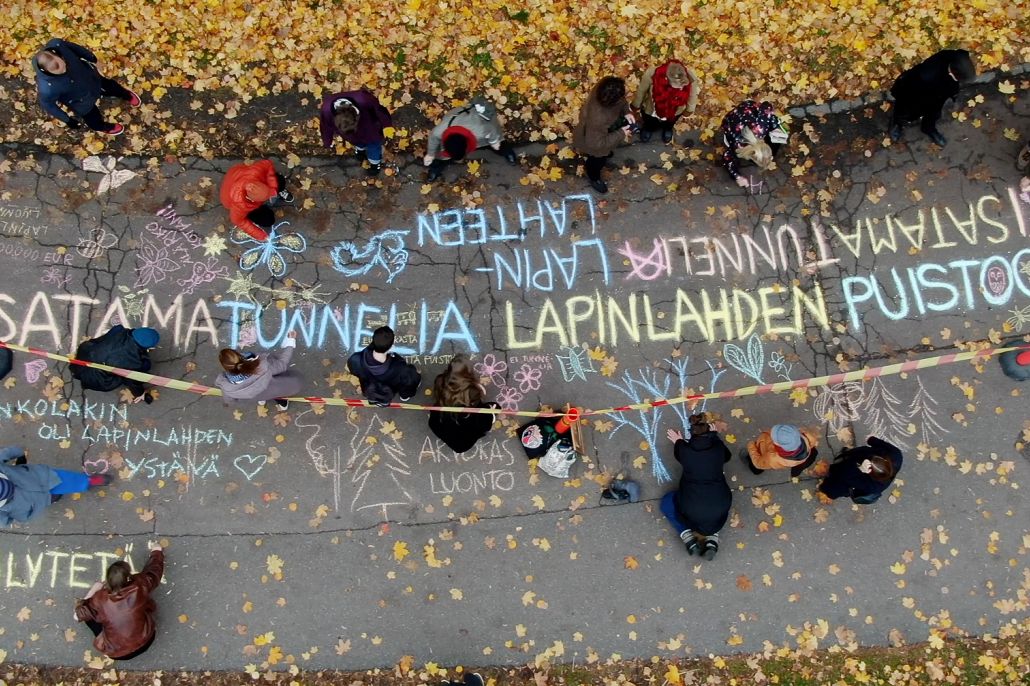 Ilmakuva kevyen liikenteen väylästä, jolla ihmiset kirjoittavat mielipiteitä liidulla asfalttiin