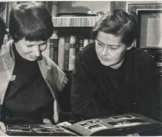 Helvi Juvonen ja Sirkka Meriluoto katselevat pöydällä olevaa valokuva-albumia.