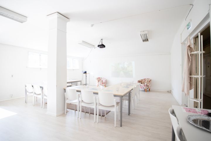 Kuvassa on pöytiä, tuoleja ja Pylvässalin pylväs.