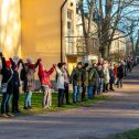 Vuoden 2018 Muuri-tapahtumassa päärakennuksen seinän edessä seisoo ihmisiä käsi kädessä silmänkantamattomiin.
