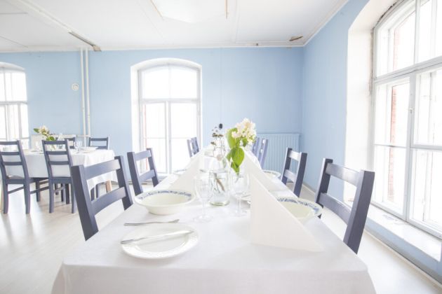 Kuvassa etualalla on katettu pöytä astioineen.