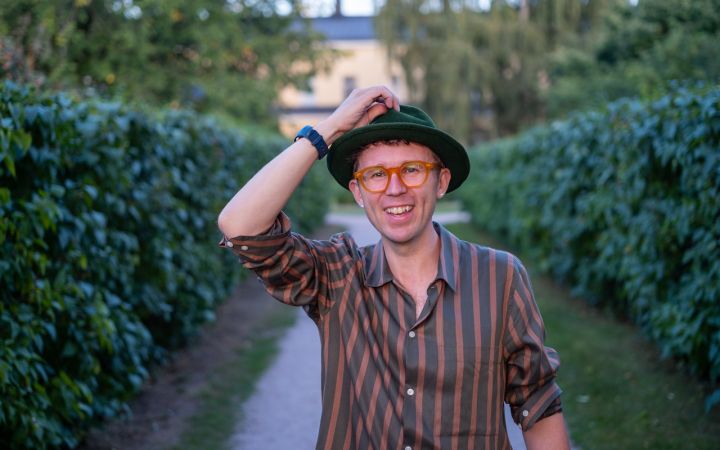 Kuvassa on hattupäinen, hymyilevä mies.