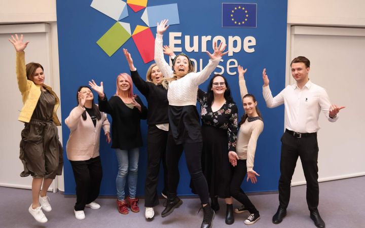 Kuvassa joukko iloisia ihmisiä Europe-kyltin edessä.