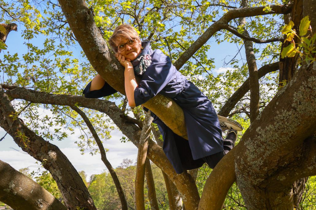 Kuvassa nainen kiivennyt puuhun