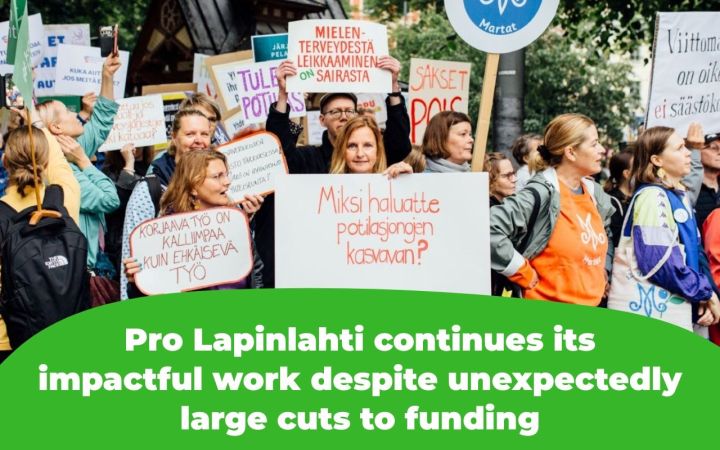 The picture shows protesters holding signs that read, among other things, "Why do you want patient queues to grow?" and "Corrective work is more expensive than preventive work" and "Cutting mental health services is sick."