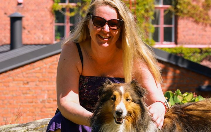 Pitkähiuksinen nainen ja pitkäkarvainen koira auringossa Lapinlahdessa.