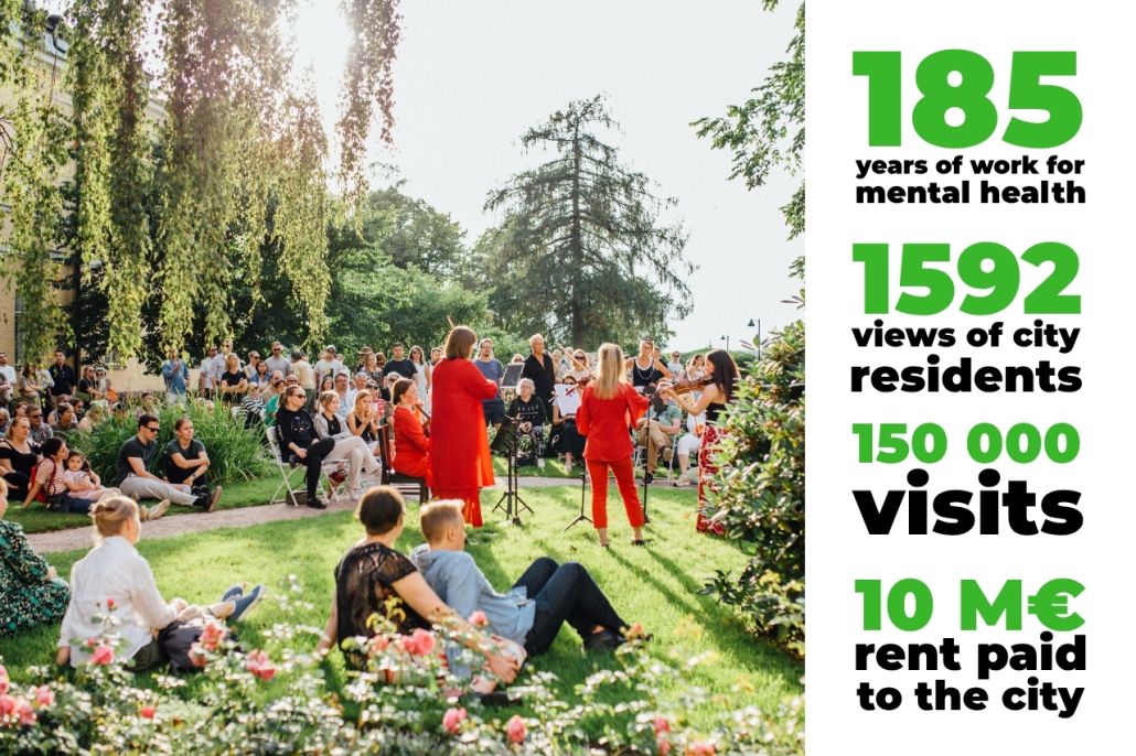 A group of people have gathered in the sunny garden to listen to a concert by a violin trio.