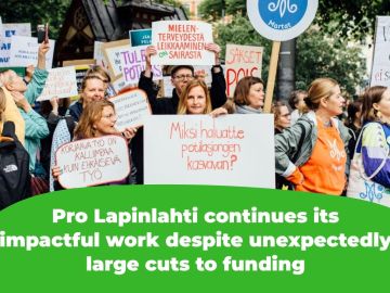 The picture shows protesters holding signs that read, among other things, "Why do you want patient queues to grow?" and "Corrective work is more expensive than preventive work" and "Cutting mental health services is sick."