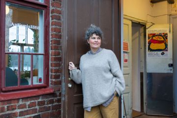 Nainen seisoo avatun oven edessä.