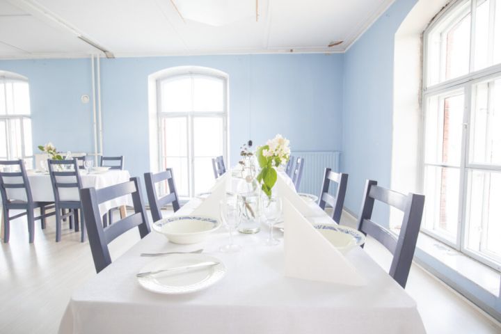 Kuvassa etualalla on katettu pöytä astioineen.