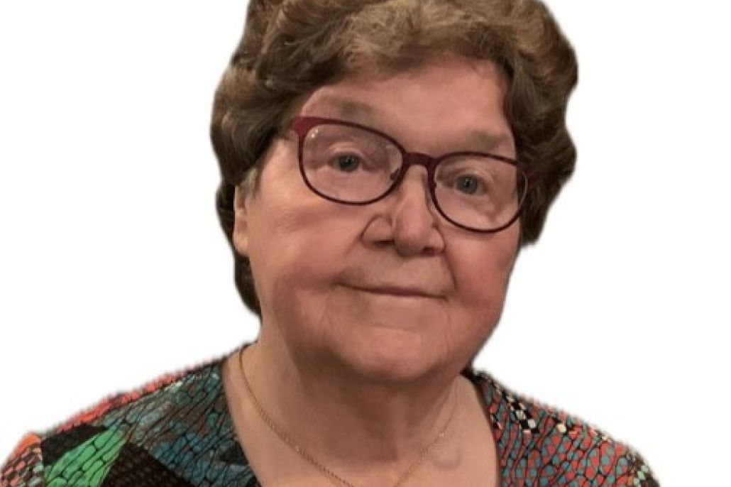 Lähikuva hymyilevästä naisesta, jolla on lyhyet hiukset ja punaiset silmälasit.