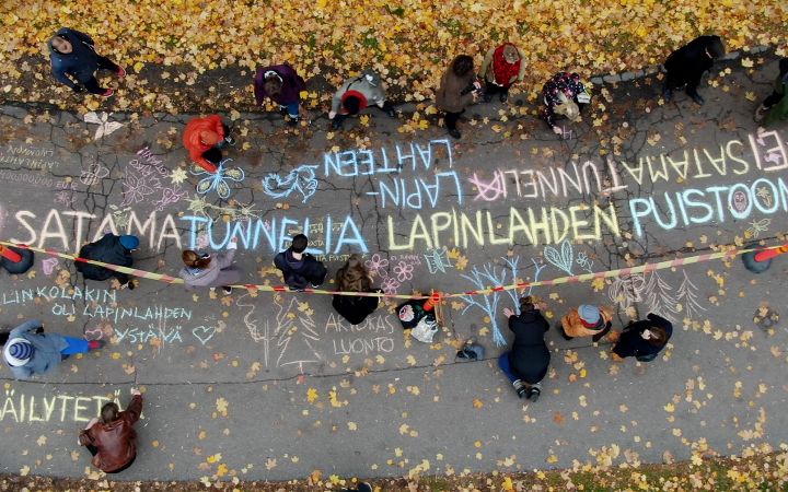 Ilmakuva kevyen liikenteen väylästä, jolla ihmiset kirjoittavat mielipiteitä liidulla asfalttiin