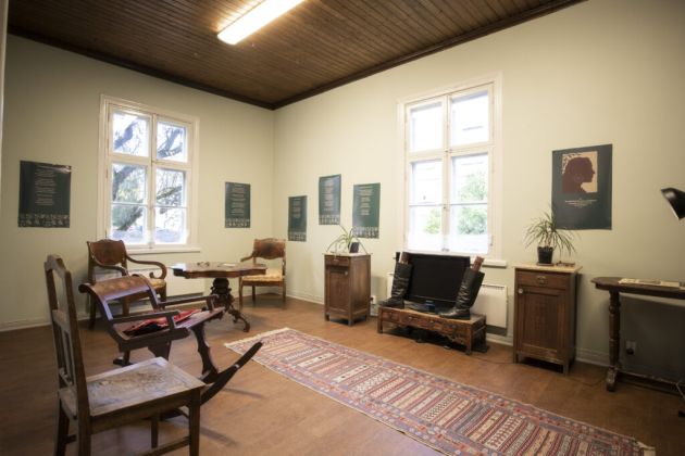 Kuvassa on seinän vieressä olevia huonekaluja. Etualalla on matto.