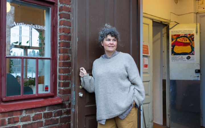 Nainen seisoo avatun oven edessä.